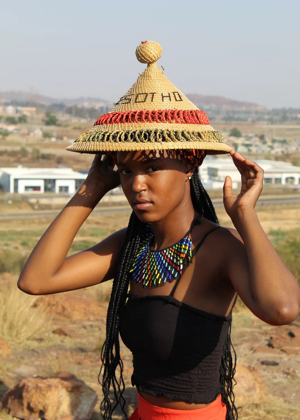 A woman wearing a traditional woven Basotho grass hat and beaded necklace (representative photograph, not Lesedi's own homestead)