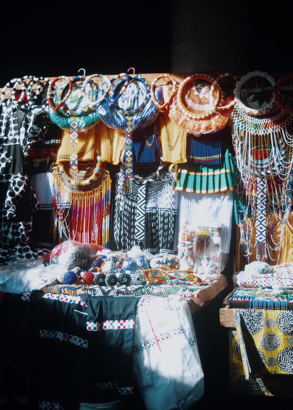 A market stall hung with colourful Zulu beadwork, skirts and necklaces (representative photograph, not Lesedi's own homestead)